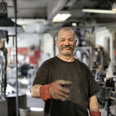 ميكانيكي مبتسم بقفازات حمراء في ورشة سيارات - كراج متنقل